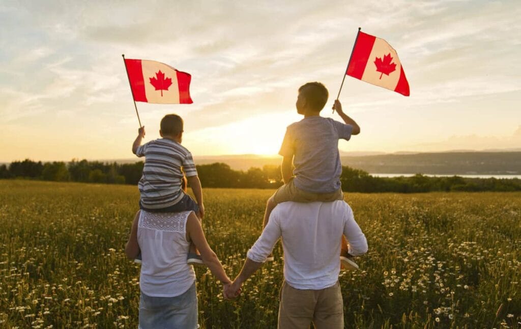 couple having child on their shoulder waving Canadian flags